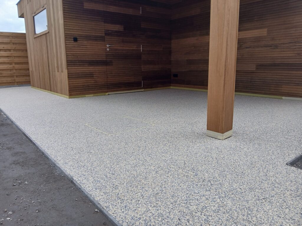 Terradec en Vuba steentapijt aangebracht door Xtraverde op terras naast houten schuur in Poperinge