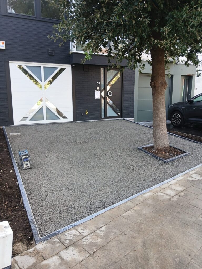 Terradec en Vuba steentapijt aanleg bij moderne woning met boom en oprit in Poperinge door Xtraverde