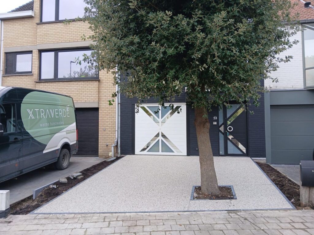 Oprit met Terradec en Vuba steentapijt professioneel geplaatst door Xtraverde uit Poperinge met boom centraal