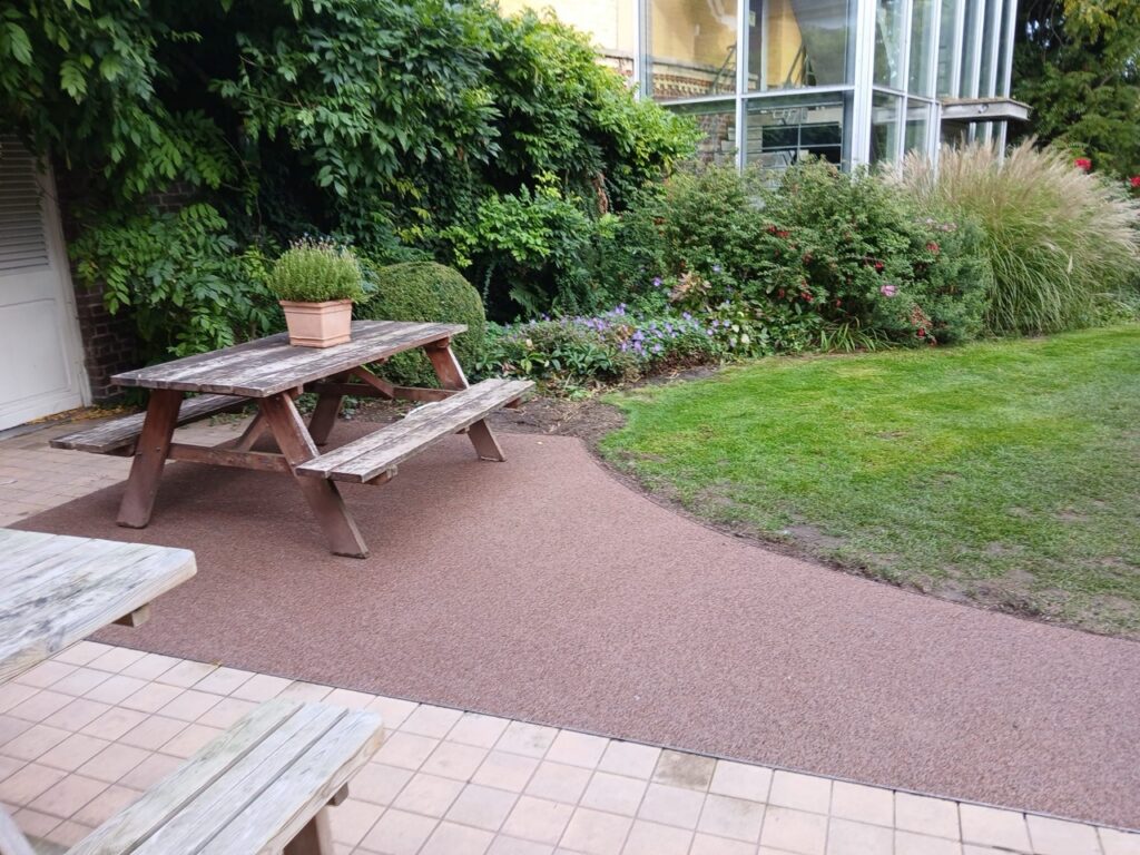 Terradec en Vuba steentapijt naast houten picknicktafel in tuin met gras en beplanting